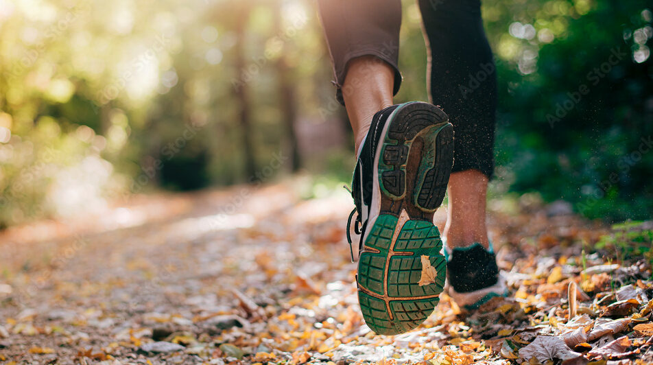 Closeup of running shoe of the person running in the nature with beautiful sunlight.